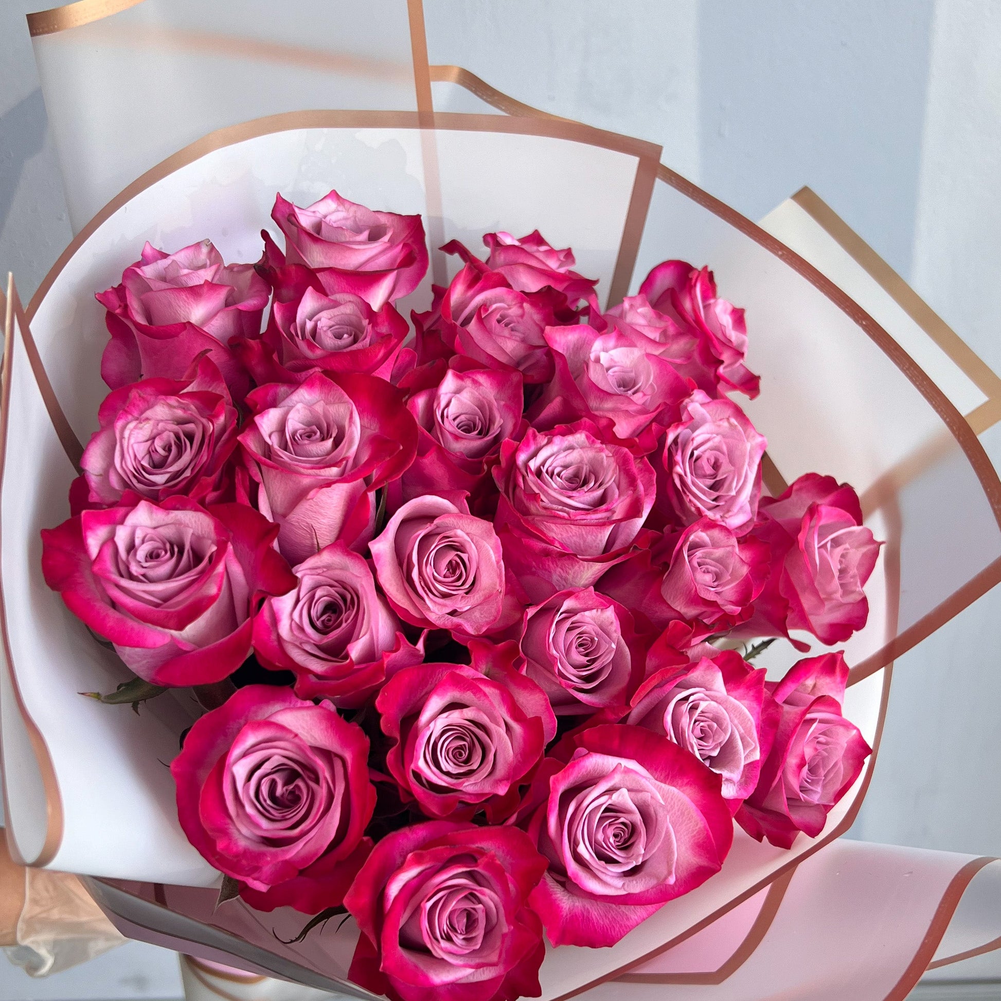 A white box filled with a bouquet of pink roses, artfully wrapped, capturing the essence of floral beauty