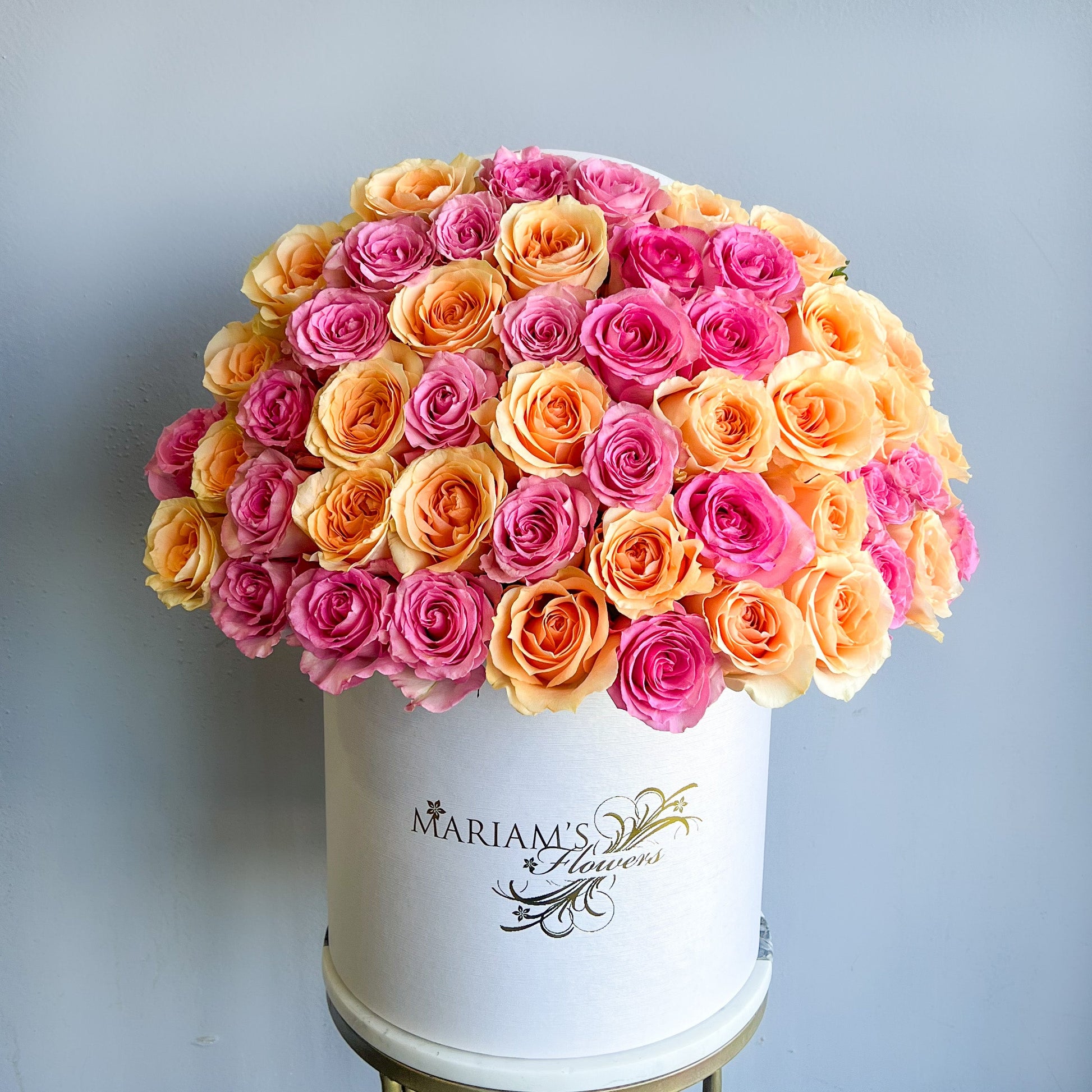 A white box filled with pink and orange roses, designed for Mother's Day, showcasing a classic floral arrangement