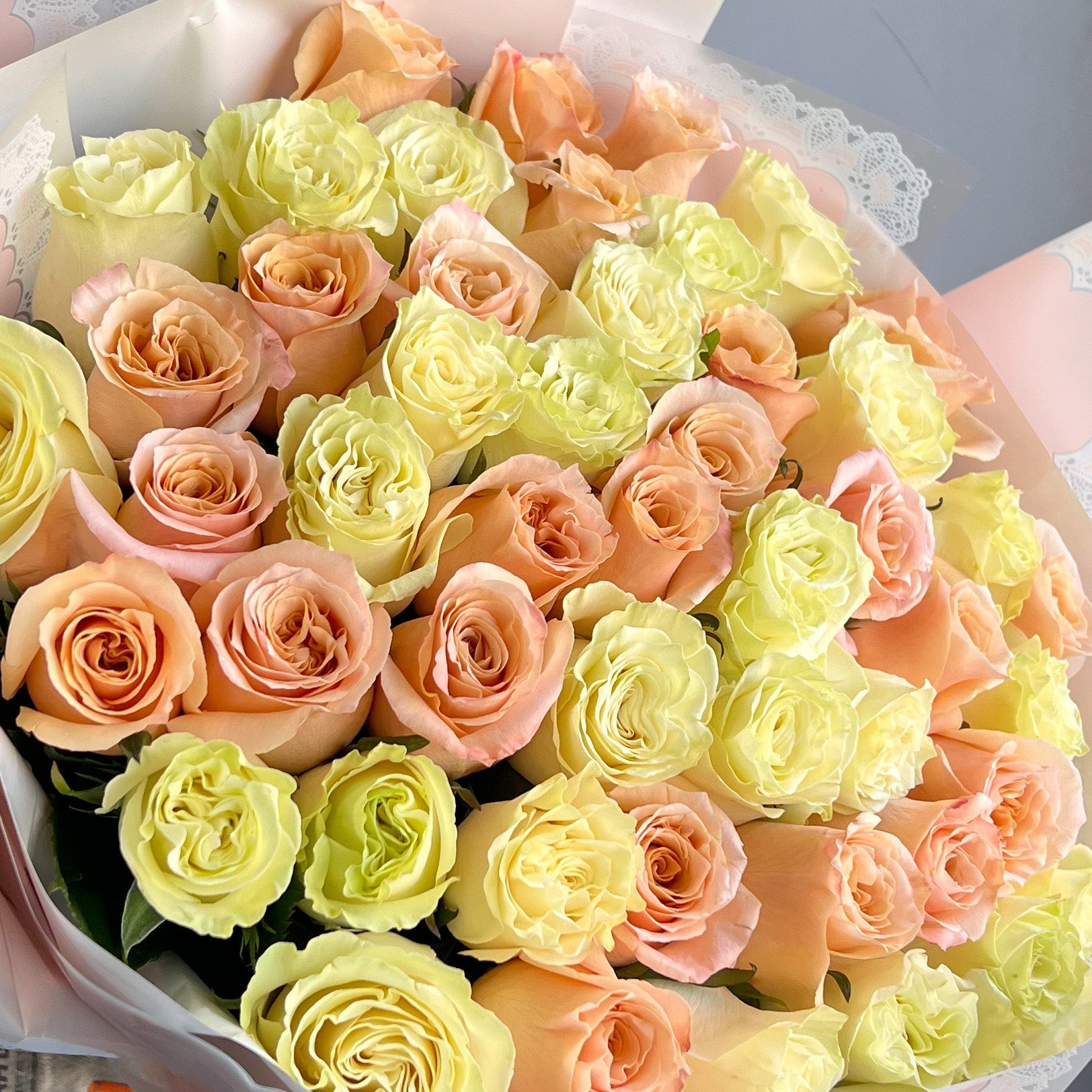 A bouquet of white and peach roses elegantly arranged in a white box, showcasing their natural beauty without fillers.