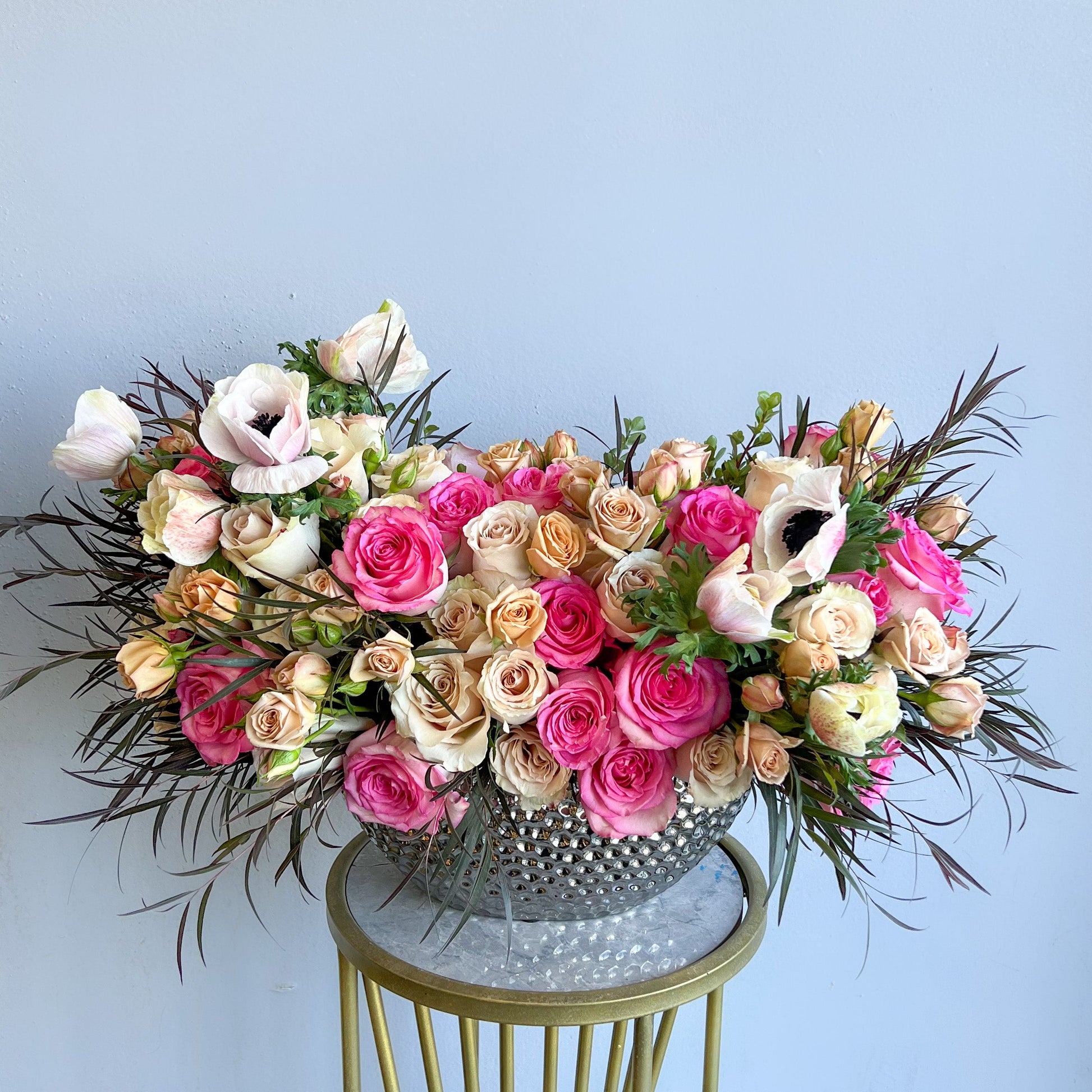 A large silver bowl filled with a vibrant arrangement of pink, white flowers, showcasing Wild Rose and Box & Vase designs