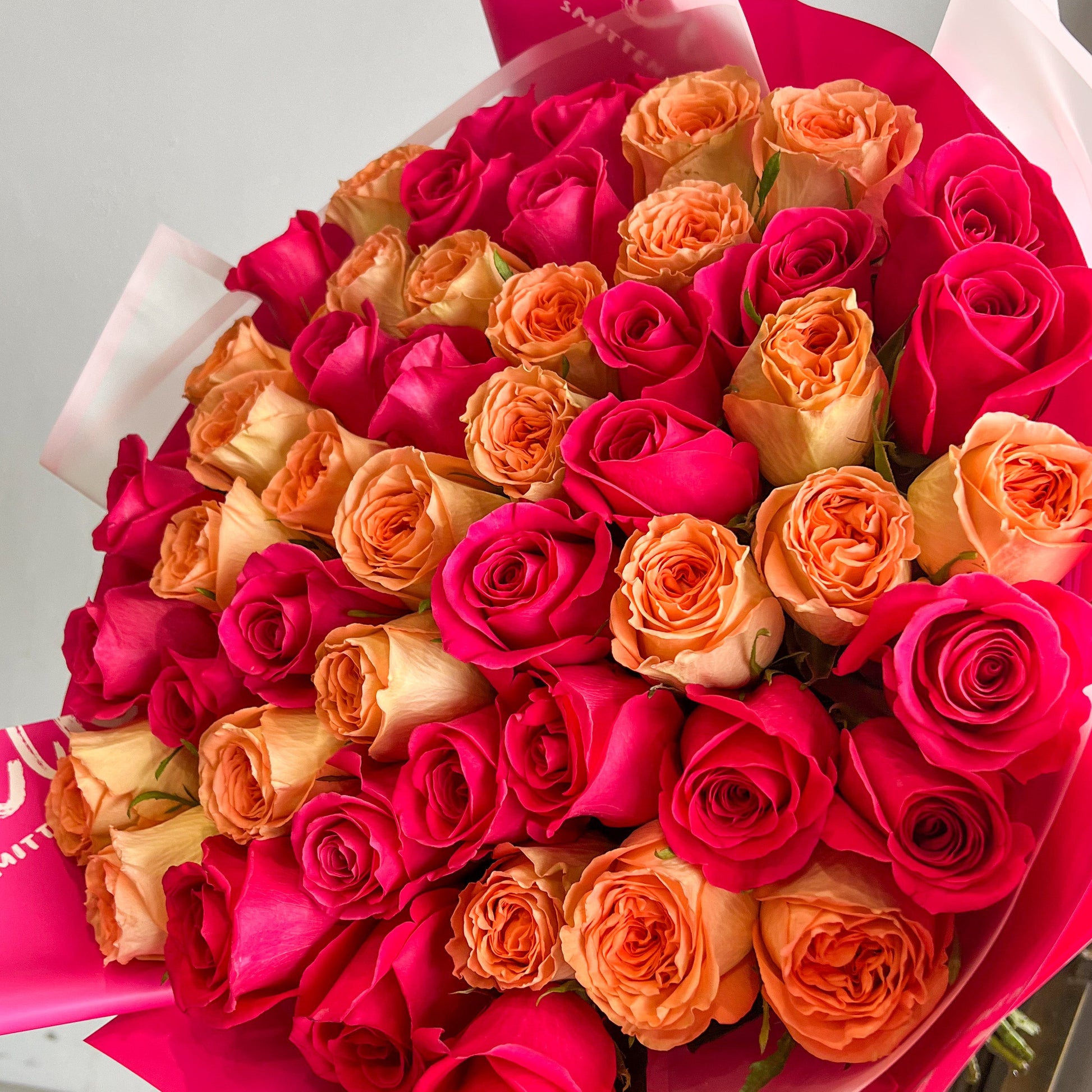 A striking bouquet featuring hot pink and orange roses, elegantly arranged with no additional filler flowers.