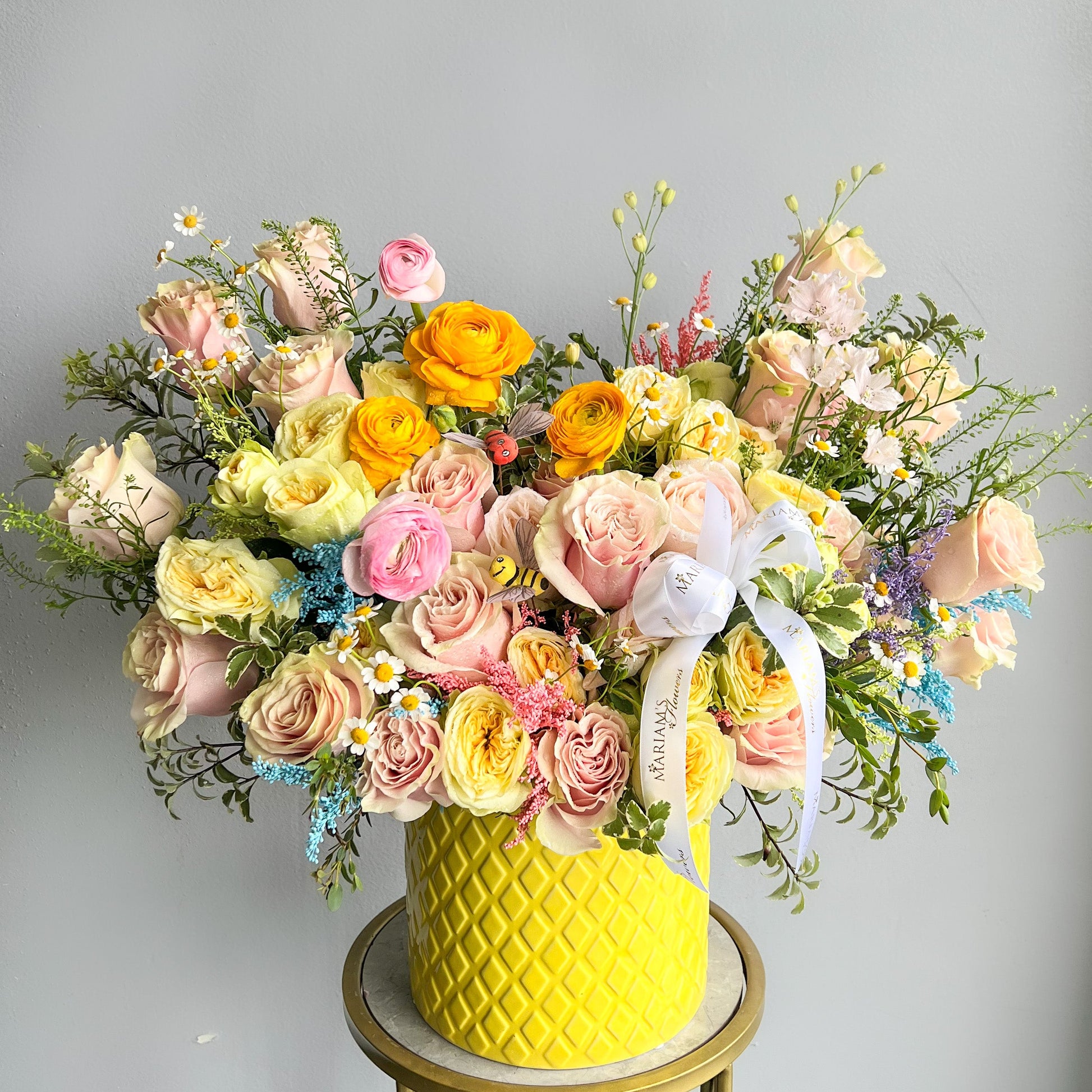 A cheerful yellow vase adorned with pink and yellow roses, capturing the spirit of spring blooms.