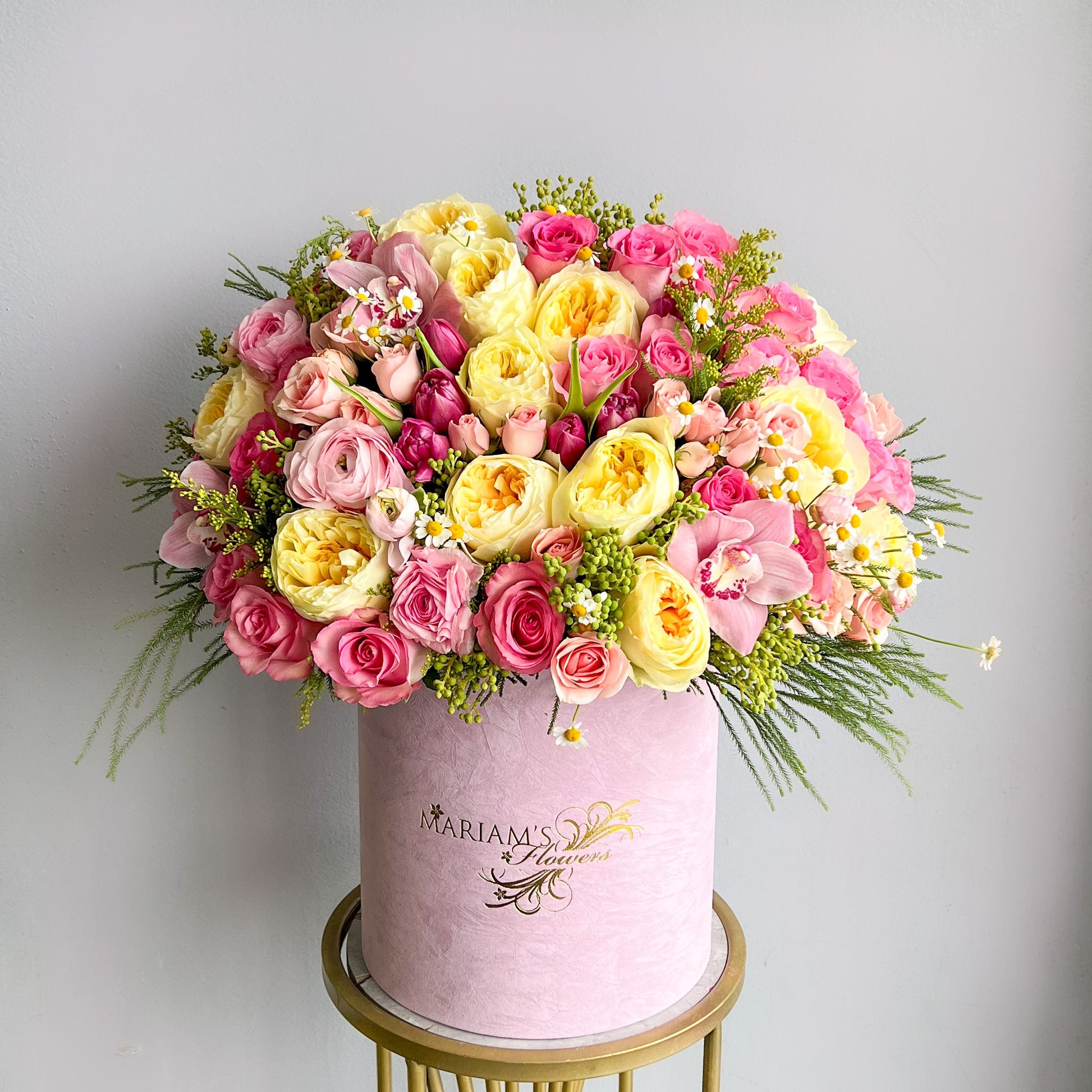 A round box filled with a vibrant pink flower arrangement, labeled "Sunshine & Rosé."