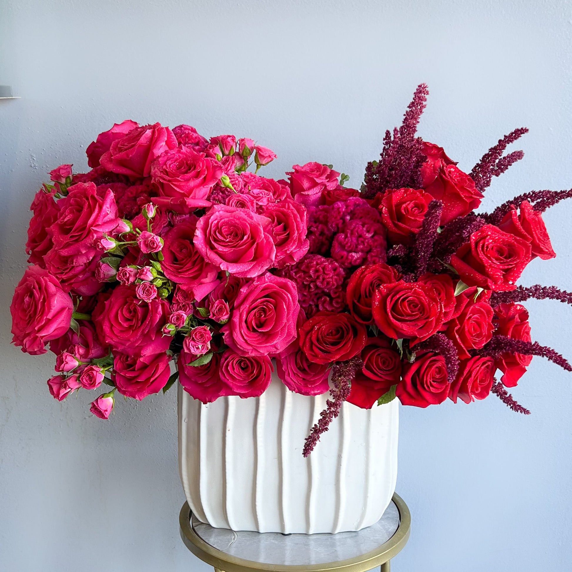 A white vase filled with striking red roses and red carnations, exemplifying a bold duo in floral design