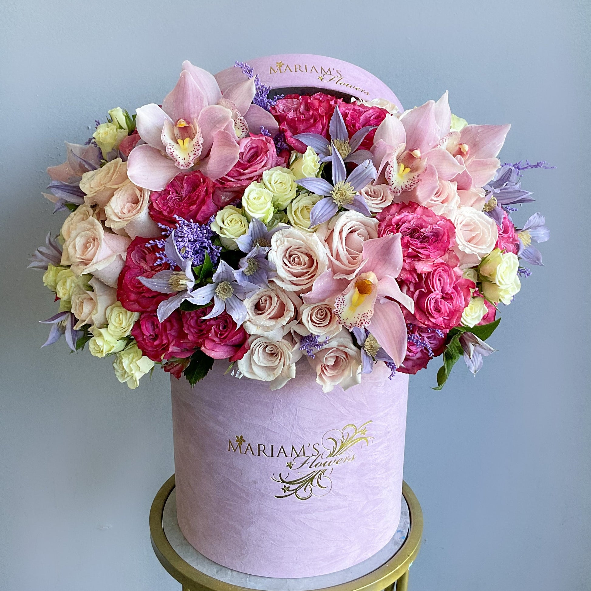 A large pink box adorned with a vibrant arrangement of flowers on top, showcasing a beautiful floral display