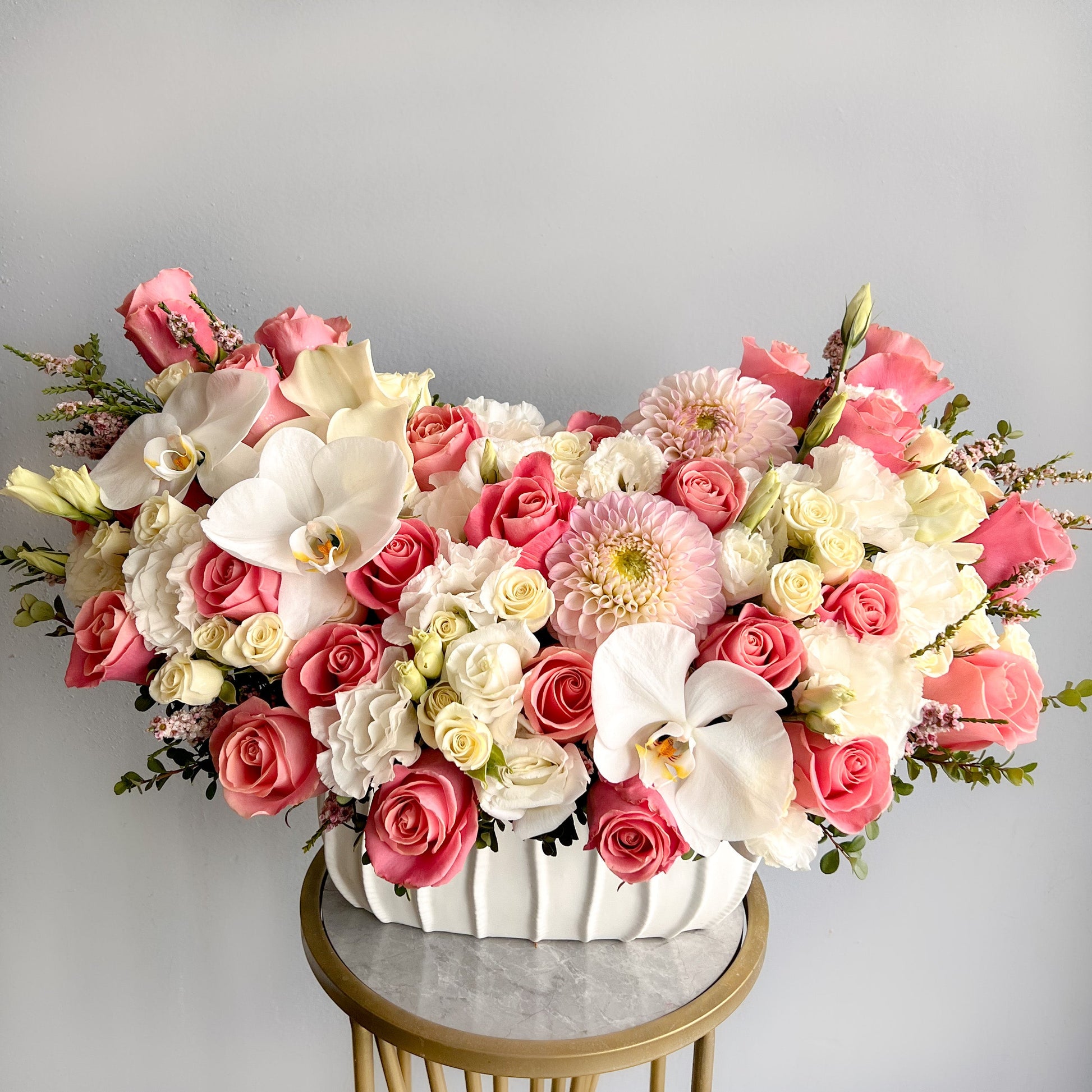 A white vase containing pink and white flowers, representing the theme "Simply Sweet" in a charming floral display.