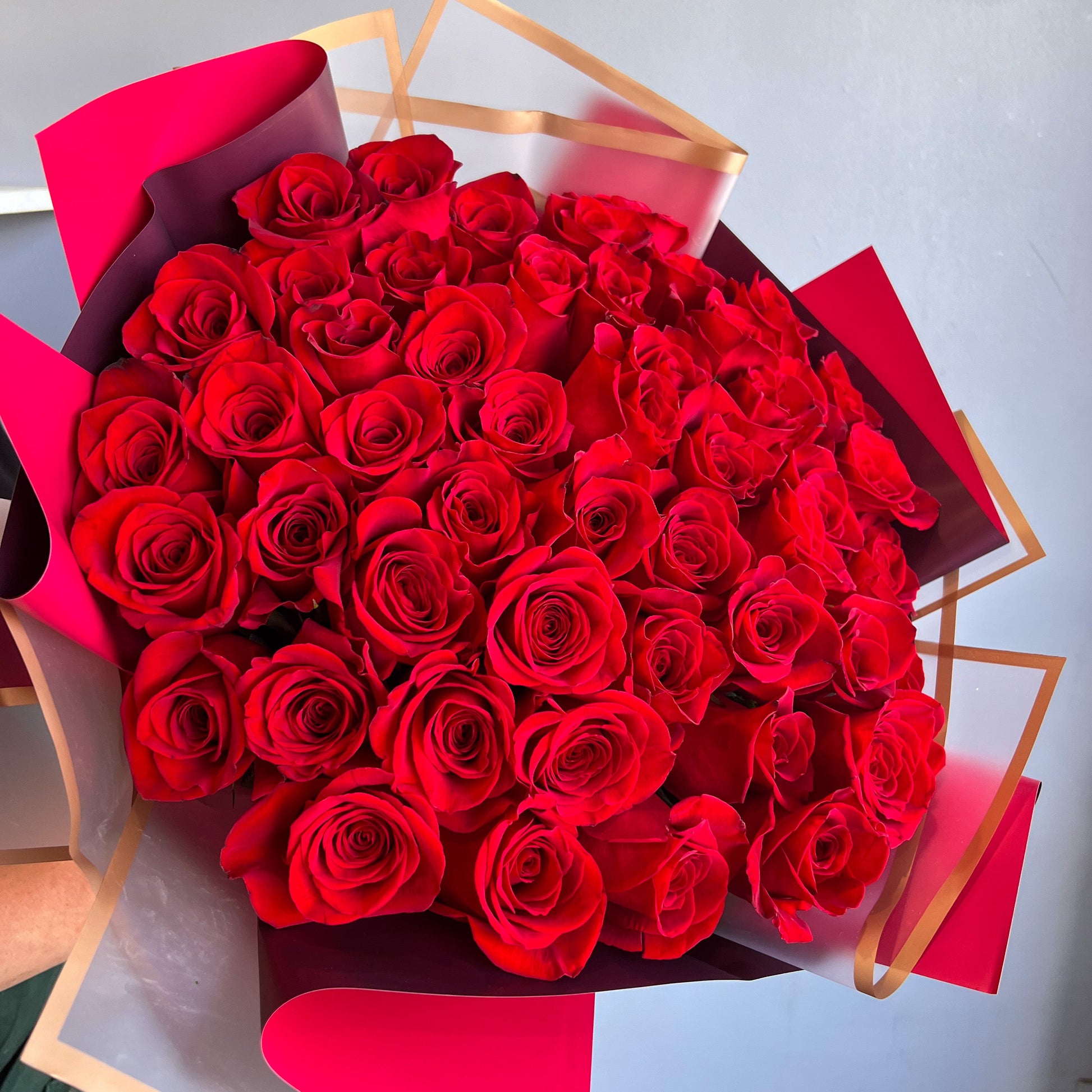A beautiful arrangement of 50 red roses presented in a striking red box, highlighting their rich color and elegance